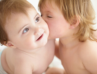 Theres no rivalry between these siblings. Closeup of a sweet little girl giving her baby sister a kiss on the cheek.