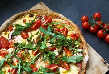 Freshly baked whole-grain sesame pizza with arugula, tomato, olive, mushroom, hollandaise sauce and...
