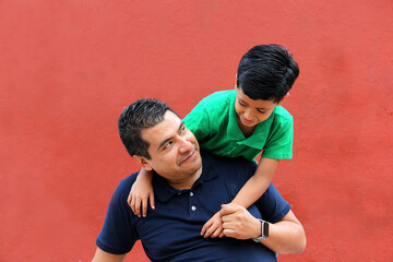 Single dad and dark-haired Latino son play and have fun together spending quality family time on...