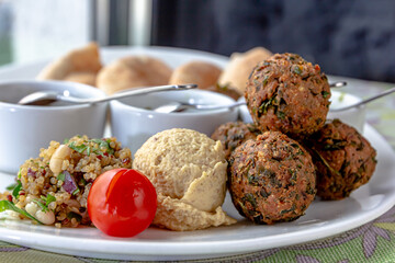Traditional middle eastern homemade dishes falafel, pita, hummus and chickpea served with vegetables and spices on woodwn table