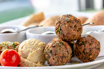 Traditional middle eastern homemade dishes falafel, pita, hummus and chickpea served with vegetables and spices on woodwn table