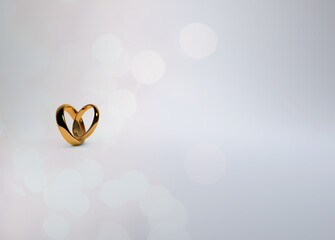 Gold wedding rings positioned to form a heart with sparkling reflections on a soft white background for save the date, invitations and place cards.