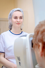 A girl optometrist examines the eyes of a patient using special modern equipment