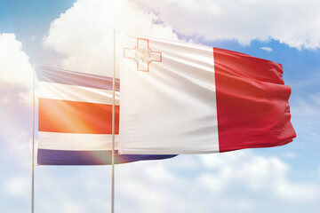 Sunny blue sky and flags of malta and costa rica