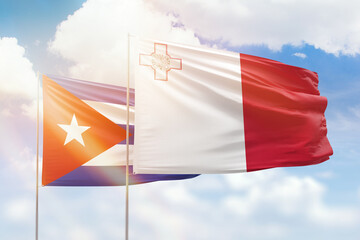 Sunny blue sky and flags of malta and cuba