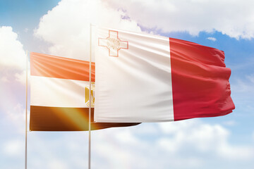 Sunny blue sky and flags of malta and egypt