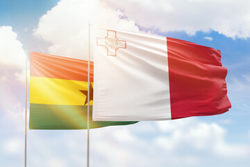 Sunny blue sky and flags of malta and ghana