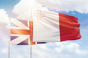 Sunny blue sky and flags of malta and great britain