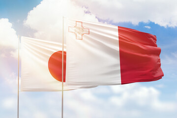 Sunny blue sky and flags of malta and japan