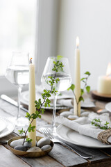 Rustic zero waste wedding decor with natural elements. Wooden table, candles, linen napkins, branches with green leaves. Eco-friendly decoration for the special dinner. Romantic and cozy place