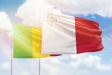 Sunny blue sky and flags of malta and mali