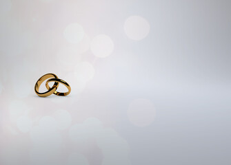 Interlocking gold wedding rings on a soft white background with sparkling reflections for save the...
