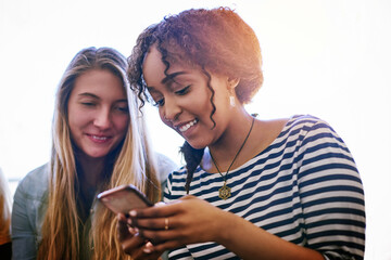 Theres wifi all around campus. Shot of two university students using a cellphone at campus.