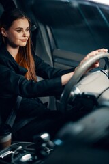 Fototapeta na wymiar vertical photo of a pleasant, relaxed woman sitting behind the wheel of a car with a seat belt fastened, smiling pleasantly. Photography at night