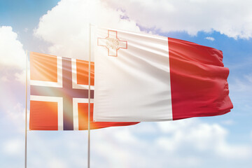 Sunny blue sky and flags of malta and norway