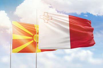 Sunny blue sky and flags of malta and north macedonia