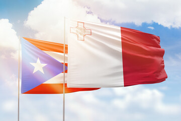 Sunny blue sky and flags of malta and puerto rico