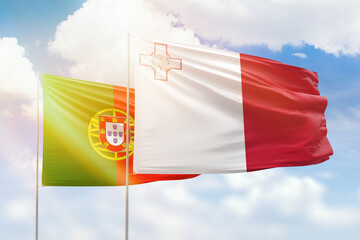 Sunny blue sky and flags of malta and portugal