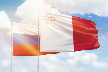 Sunny blue sky and flags of malta and russia