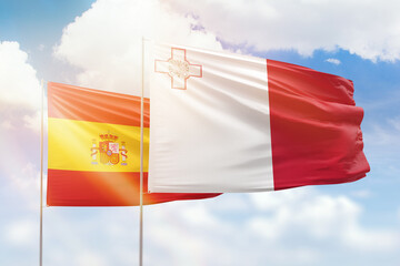 Sunny blue sky and flags of malta and spain