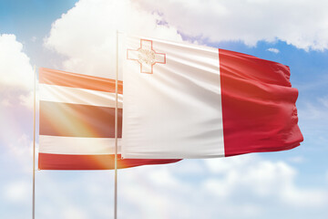 Sunny blue sky and flags of malta and thailand