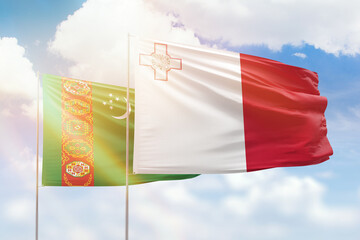 Sunny blue sky and flags of malta and turkmenistan