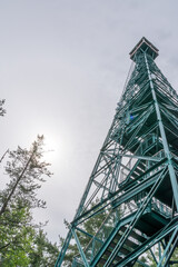 A tourist stands at the bottom of the fire tower in the White Bear Forest near Temagami, Ontario, looking up towards the top.