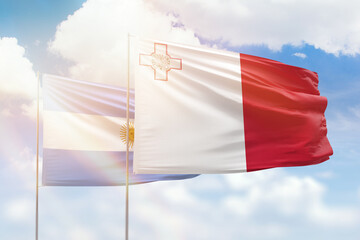 Sunny blue sky and flags of malta and argentina