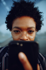 4k. Charming African American woman in modern striped suit. Holding her phone looks in camera....
