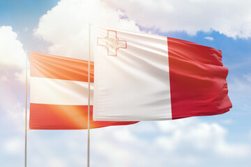Sunny blue sky and flags of malta and austria