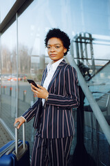 4k. Travel, Digital. Charming African American woman in modern striped suit with luggage and...