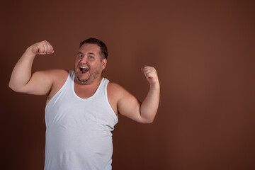 An angry fat guy in a white T-shirt screams in disgust against a brown background.
