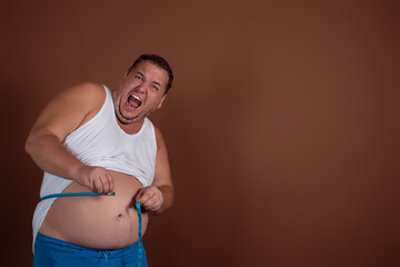 Funny fat man goes in for sports with dumbbells on a brown background. Diet and weight loss.