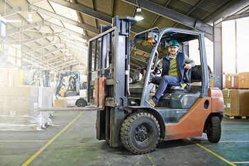 Fototapeta na wymiar Time to get things moving around here. Portrait of driver in a forklift on the factory floor.