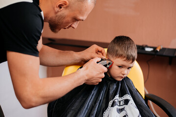 Boy haircut by master hairdresser with machine