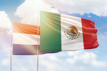 Sunny blue sky and flags of mexico and netherlands