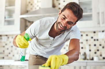 He loves it when things are clean. Cropped shot of a handsome young man cleaning his kitchen at home.