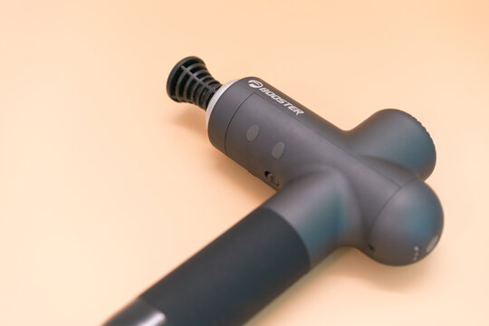 New York, USA - Jun 17, 2022: The Booster percussion massage gun lies on a yellow background. Stimulation. Tool. Care. Restoring. Vibration. Equipment. Assistance. Electronic. Fitness. Health Care