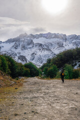 Fototapeta na wymiar a man walking on a path that leads towards the snowy mountains