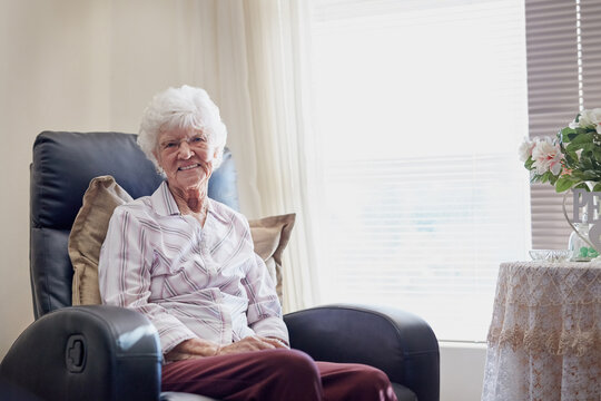 I Sure Am Glad I Planned For A Relaxing Retirement. Portrait Of A Happy Elderly Woman Relaxing On A Chair At Home.