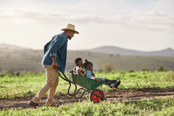 Its not a farm without a family. Shot of a mature man working his adorable son and daughter on a...