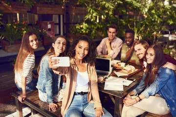 Im just here for the selfies. Cropped shot of an attractive young woman taking a selfie while out for lunch with friends.