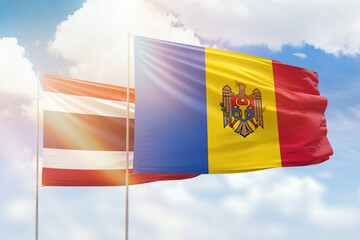 Sunny blue sky and flags of moldova and thailand