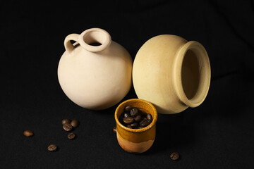 Clay jug and pot with coffee beans. Close-up