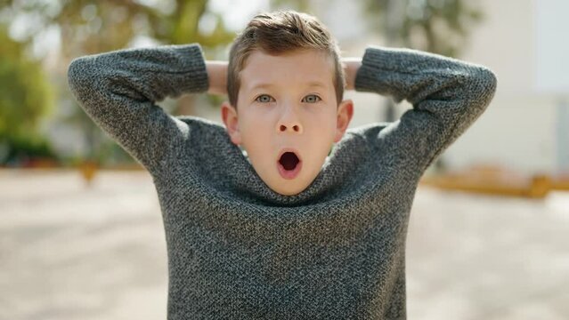 Blond child standing with surprise expression at park