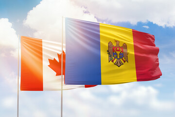 Sunny blue sky and flags of moldova and canada