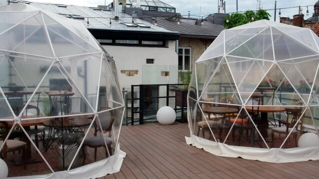 Glass terrace on a cloudy autumn day. Silhouette of a table with service inside. An exciting gastronomic experience in a special place.