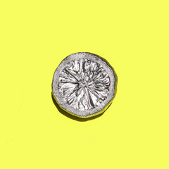 Silver lemon on vivid yellow background. Minimalistic modern composition. Nature flat lay idea. Summer flat lay.