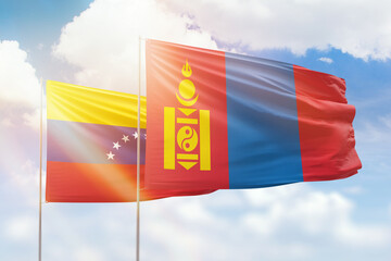 Sunny blue sky and flags of mongolia and venezuela