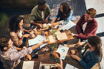 This lunch is bringing out the best in this meeting. Shot of a group of creative workers having a meeting over lunch in a cafe.